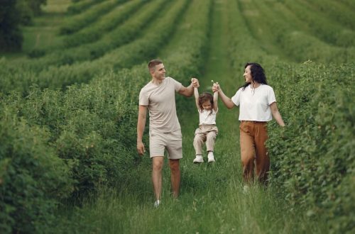 A happy family walking in a lush, green rural field together.