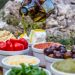 Outdoor picnic with various Mediterranean spreads, herbs, and olive oil drizzle.